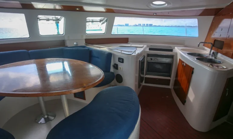 Soft cushion, wooden table and kitchen from 4 vents catamaran
