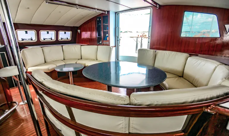 Semicircle soft cushions and wooden tables inside tiare catamaran