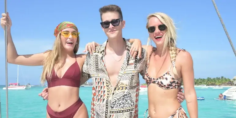 Guy with two chicks in a catamaran party